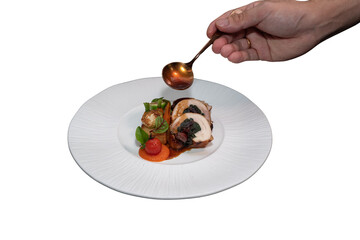 A chef delicately pours sauce onto a gourmet dish on a white plate, showcasing culinary expertise