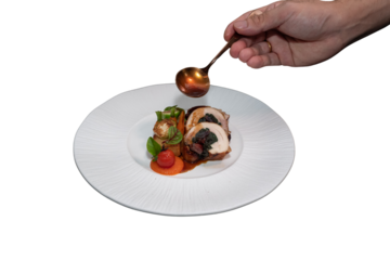 A chef delicately pours sauce onto a gourmet dish on a white plate, showcasing culinary expertise