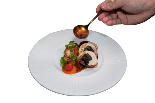 A close-up shot of a gourmet dish being expertly plated and sauced. A chef's hand delicately garnishes the meal with sauce