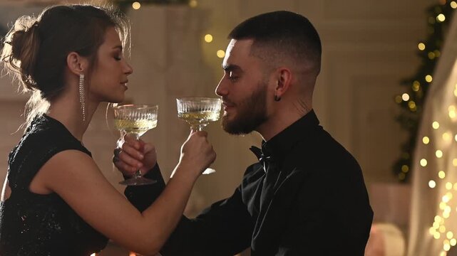A young couple in love celebrates Christmas and New Year's in a romantic atmosphere with champagne, toasting and making wishes. A kiss on the shoulder on brotherhood