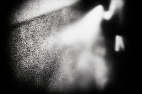 Grainy monochrome abstract background with blurred light, soft edges, high contrast shadows and faded neutral tones