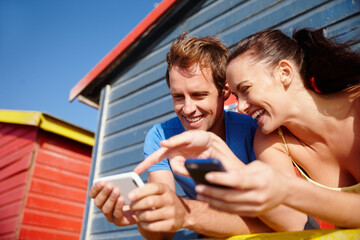 Phone, happy and couple at beach with social media, connectivity or communication on mobile app. Technology, smile and man with woman on cellphone for contact, texting or chatting online by ocean.