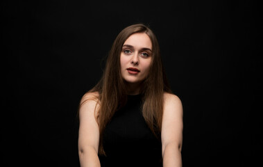 Fototapeta premium Calm young woman with long hair posing in studio portrait against dark background with soft natural expression