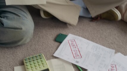 Tilt up shot of young Biracial couple sitting at home discussing overdue bills with worried expressions while managing household finances and planning payments - Powered by Adobe