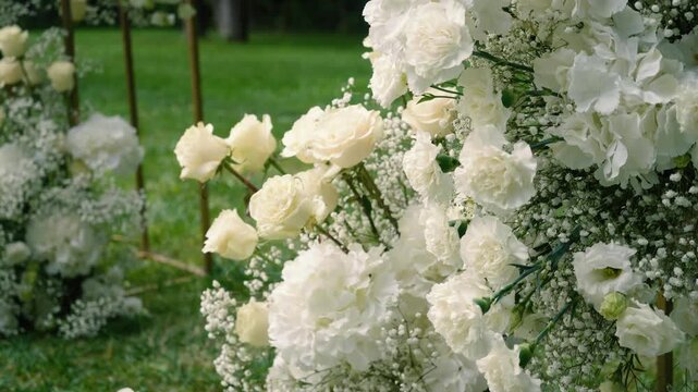Beautiful white roses and eustoma flowers with petals and a romantic atmosphere. Outdoor wedding ceremony for the bride and groom. Decor and floristry.