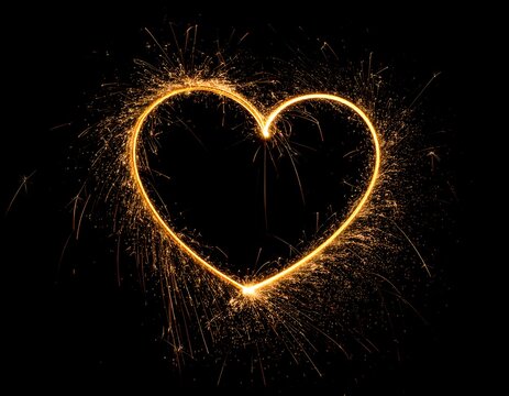 A glowing, golden heart is illuminated in the darkness, framed by sparkling light trails