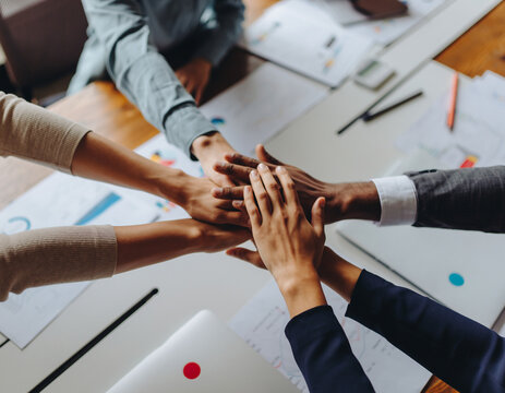 Diverse Business Team Stacking Hands Together in Unity Over Office Desk