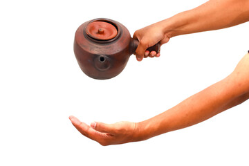 A person holding and pouring from a brown clay teapot isolated on white showing hands and arms