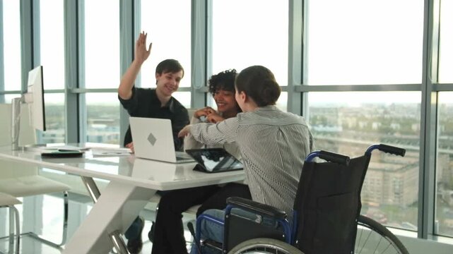 Teamwork brainstorm. Diverse multiracial colleagues woman in chair for people with disability working together. Group of people sitting in creative office discussing business. Young professional team - Powered by Adobe