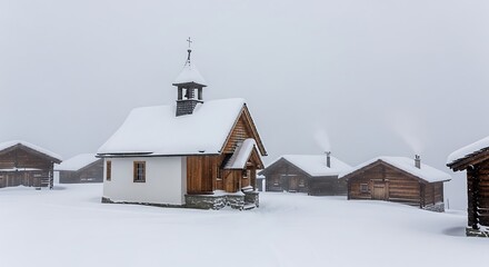 Tiny mountain village chapel and cabins stand in snowy winter fog.