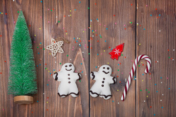 Christmas composition. A Christmas tree, two gingerbread men, and stars on a wooden background. Creative flat lay