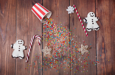 Christmas composition. Two gingerbread men, sugar stars, and scattered candies on a wooden background. Creative flat lay