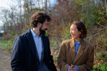 Smiling couple walks together on a sunny autumn day in a park surrounded by trees