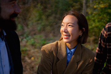 Smiling woman enjoys a sunny day outdoors in a forest with friends