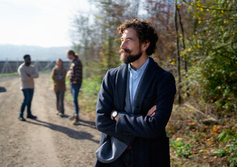 Group of friends enjoying a sunny day outdoors while a man in a blazer reflects on the peaceful surroundings