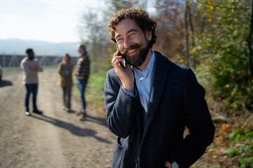 Man talking on the phone while friends stand on a sunny pathway in the countryside
