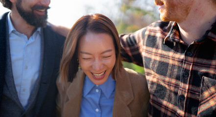 Friends enjoying a joyful moment outdoors while laughing together in warm sunlight at a park in autumn
