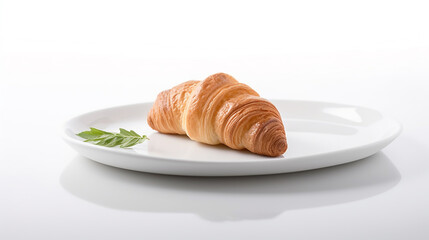 A golden brown, flaky croissant served on a simple white plate with a small green garnish, isolated on white background