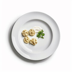 Four steamed dumplings served on a white plate with a dollop of sour cream and a sprig of fresh parsley, isolated on white background