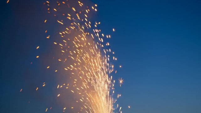 Bright Golden Sparks Erupting from a Fountain Firework Against a Deep Blue Twilight Sky, Celebrating Festive Occasions