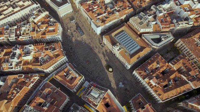 Breathtaking aerial view of Puerta del Sol in Madrid, Spain. Drone pulls back to reveal the bustling city square, historic architecture, and sprawling cityscape at golden hour.