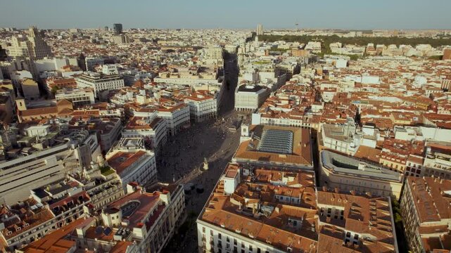 Breathtaking aerial view of Puerta del Sol in Madrid, Spain. Drone pulls back to reveal the bustling city square, historic architecture, and sprawling cityscape at golden hour.