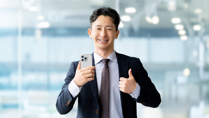 スマートフォンを持っていいね！のポーズをする男性