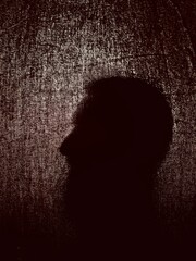 Silhouette of a person behind a dark fabric, mysterious and suggestive atmosphere, thanks to the strong backlighting that emphasizes the silhouette and the irregular texture of the fabric that creates