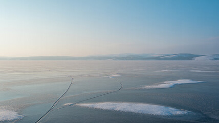 Frozen lake surface with cracks and distant mountains