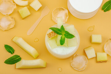 Natural melon hydrating cream with mint and ice pieces. White cosmetic jars and fresh fruit