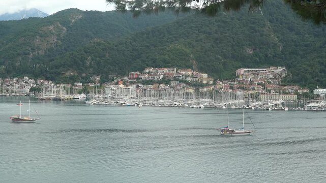 Aerial view of Fethiye marina and harbor in Turkey with numerous yachts, sailboats, and gulet boats anchored in bay with mountains