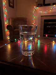 Prismatic holiday lights through glass of water on festive table