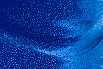 Water drop texture on blue macro beverage bottle,Macro photography of water droplets on the surface of a clear blue plastic bottle. Close-up detail, condensation, refreshing beverage, liquid texture, 