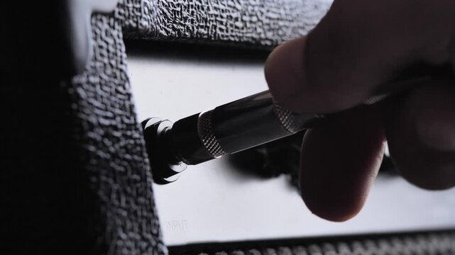 Close-up hand plugging guitar jack cable into black amplifier, capturing moment of sound setup and music creation. concept of audio, performance, practice, studio work, concerts and audio equipment