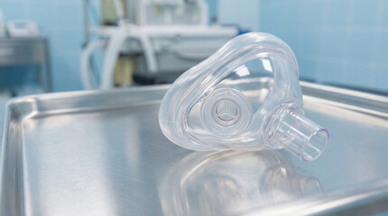 A clear anesthesia mask on a sterile steel tray in a clinical setting. STEM education sheets, lab safety posters, designed for STEM education and laboratory safety posters.