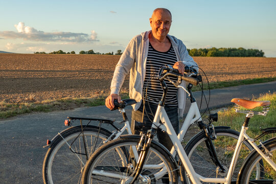 cyclist Man inflating bicycle tire outdoors in sunset light, hobby travel, repair, cycling lifestyle, countryside activity, healthy outdoor routine, connection between man and nature, rural life