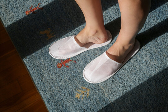 Female feet wearing white hotel slippers, view from above	
