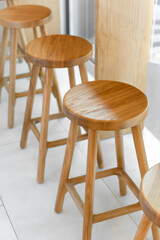 Three wooden bar stools in a row. Round wooden seats of three natural wood counter stools neara window. Rich grain and texture of the light-colored wood - clean, minimalist, Scandinavian aesthetic.