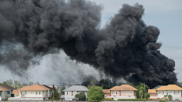 Dramatic plume of black smoke billowing over residential neighborhood