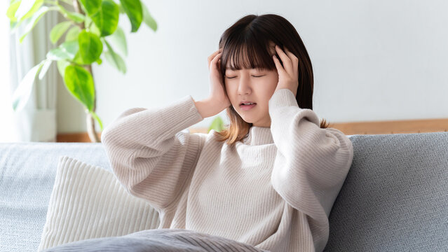 頭痛・頭を押さえて悩む女性