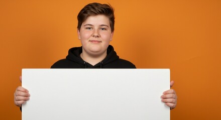 Young person holding a blank white sign in front of an orange background