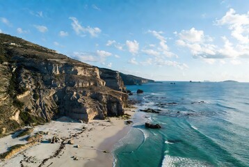Dramatic coastal cliffs, sandy beach, and turquoise ocean vista
