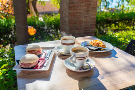 Morning outdoor coffee and breakfast served with crossaint. Selective focus on coffe glass 