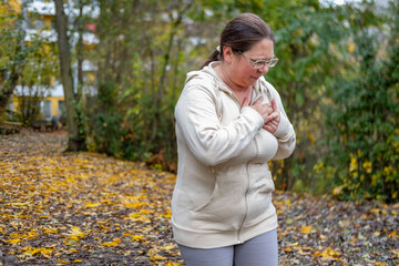 plus size woman stops during autumn run holding chest, heart discomfort, jogging, running challenge, health awareness, exercise caution, unexpected pause outdoors, outdoor fitness, active lifestyle