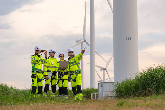 Workers conduct maintenance checks at a wind farm during late afternoon hours