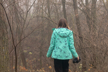 The young woman walking through a dark forest on a autumn day