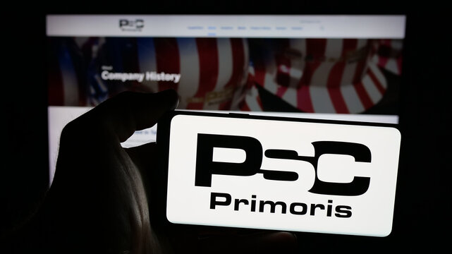 Stuttgart, Germany - 11-20-2025: Person holding mobile phone with logo of company Primoris Services Corporation (PSC) on screen in front of web page. Focus on phone display.