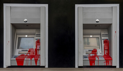 Paris, France - 06 14 2025: Two ATMs on the front of a bank painted red by vandals during a demonstration