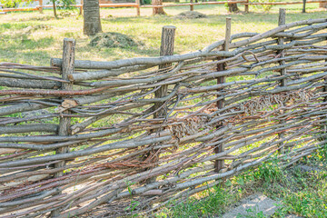 A rustic wooden fence, interlocking logs with weathered texture and green moss, in a blurred outdoor setting suggestive of a rural area or park Daytime lighting, muted colors, straightforward photog