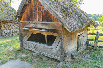 Old, weathered barn in a rural Central European setting during daylight under an overcast sky Traditional design with vertical wood planks and a gable roof showing signs of wear Sparse grass and ag